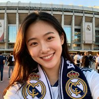 一位25岁女性球迷头像，戴着皇马围巾，在伯纳乌球场外微笑留影